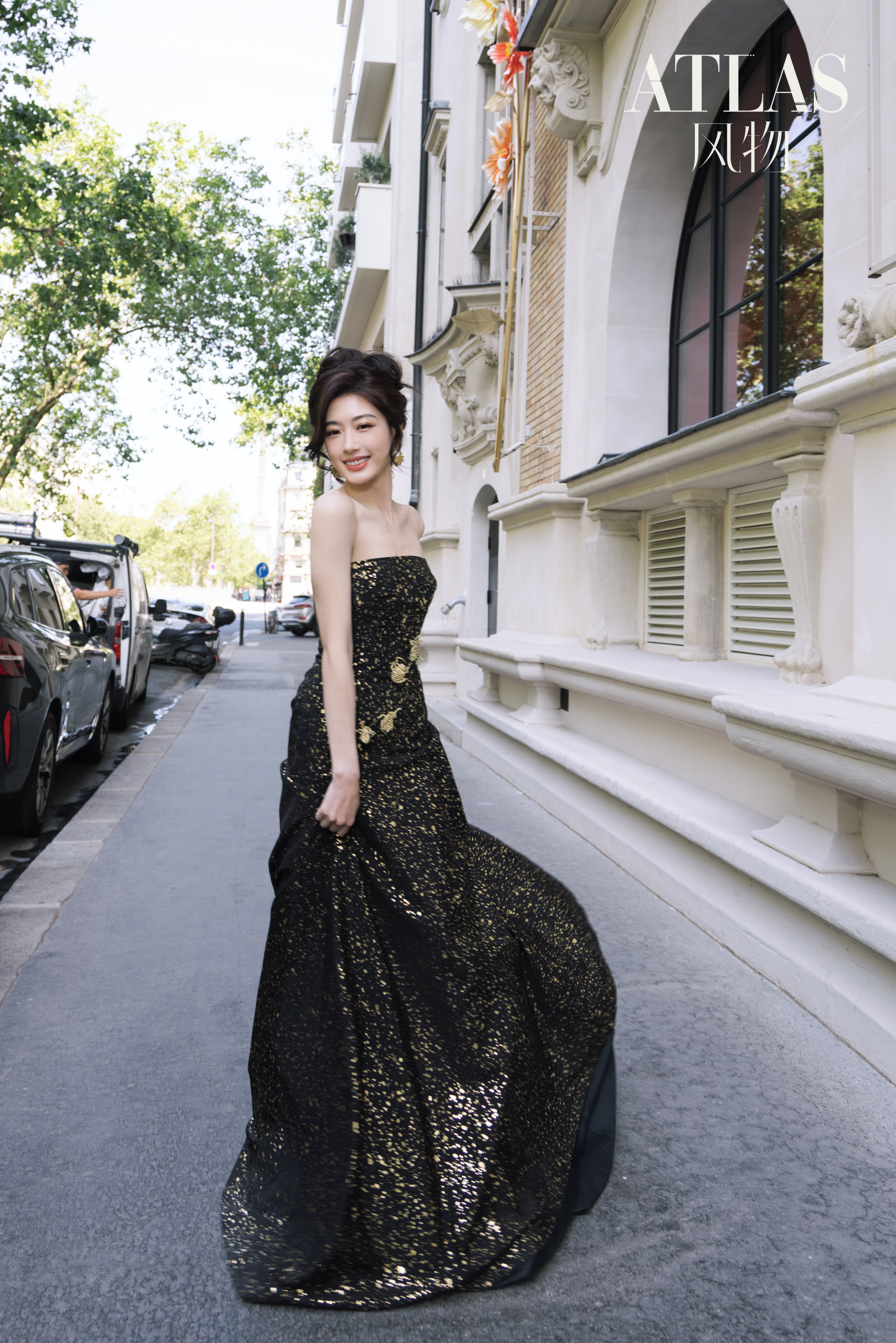 Sun Leyan smiling on a Paris street in a black-and-gold dress.
