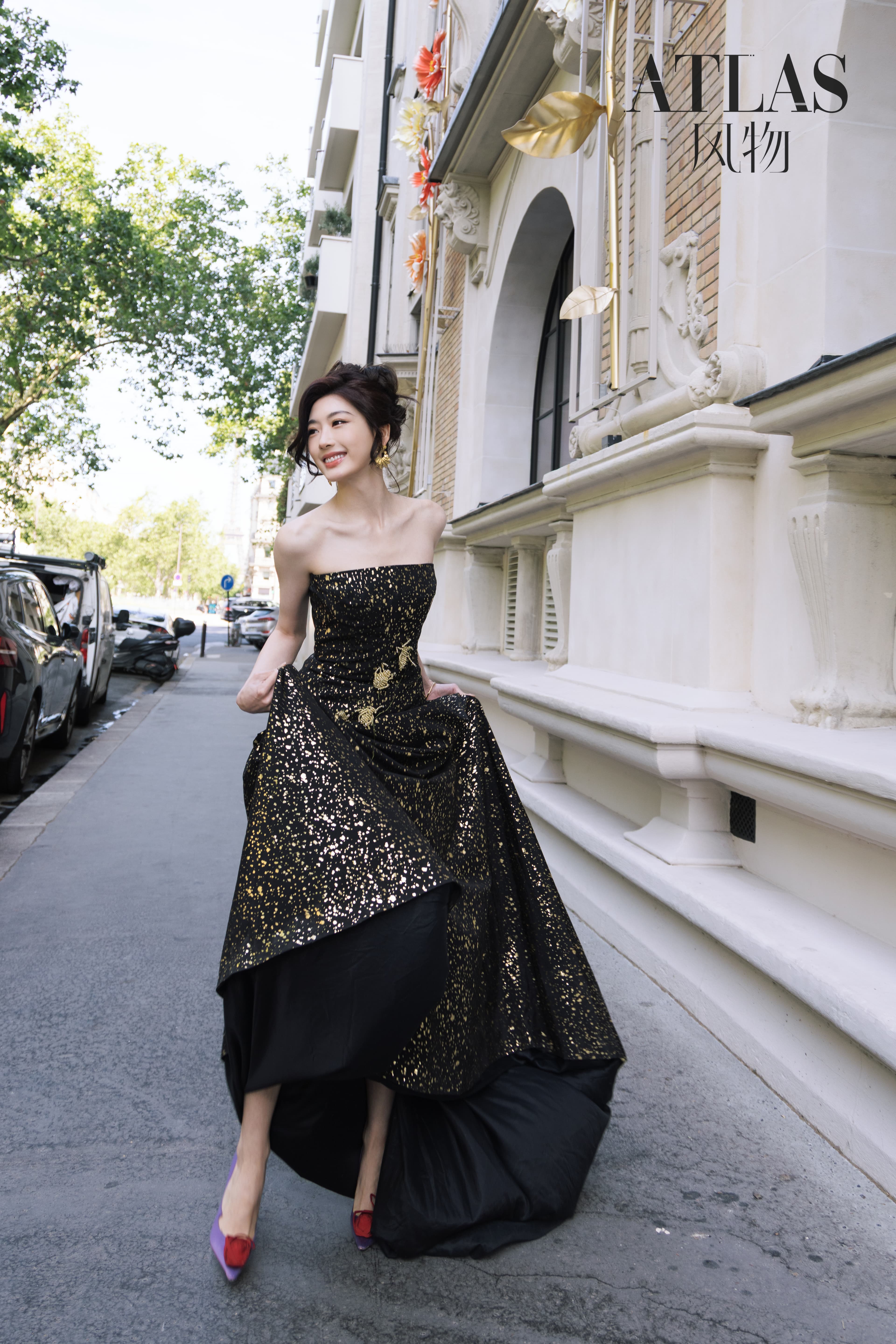 Sun Leyan seated low on a Paris street with the full black-and-gold silhouette visible.