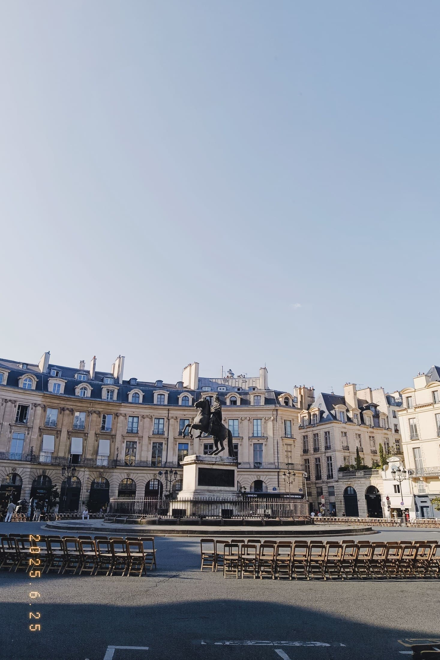 A bright Paris riverside view with pale buildings and blue sky.