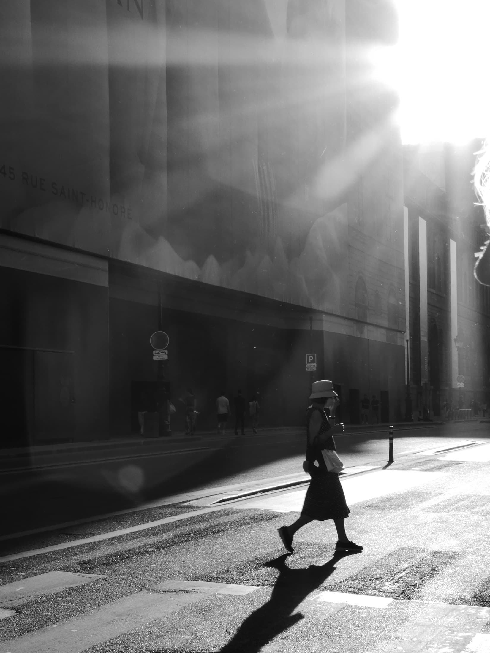 A lone figure walking through a shaft of light in Paris.